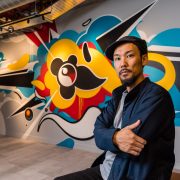 Artist Suiko in front of a piece of his grafitti