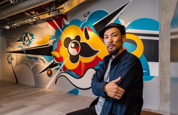 Artist Suiko in front of a piece of his grafitti