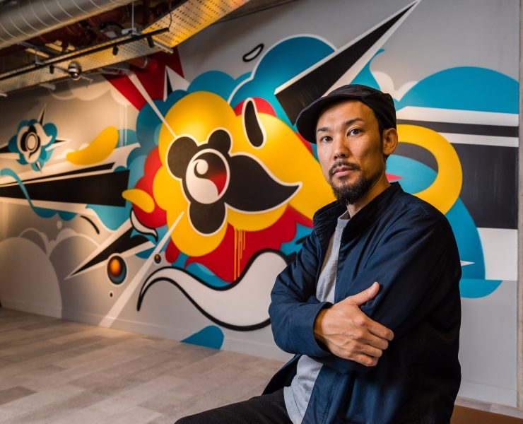 Artist Suiko in front of a piece of his grafitti