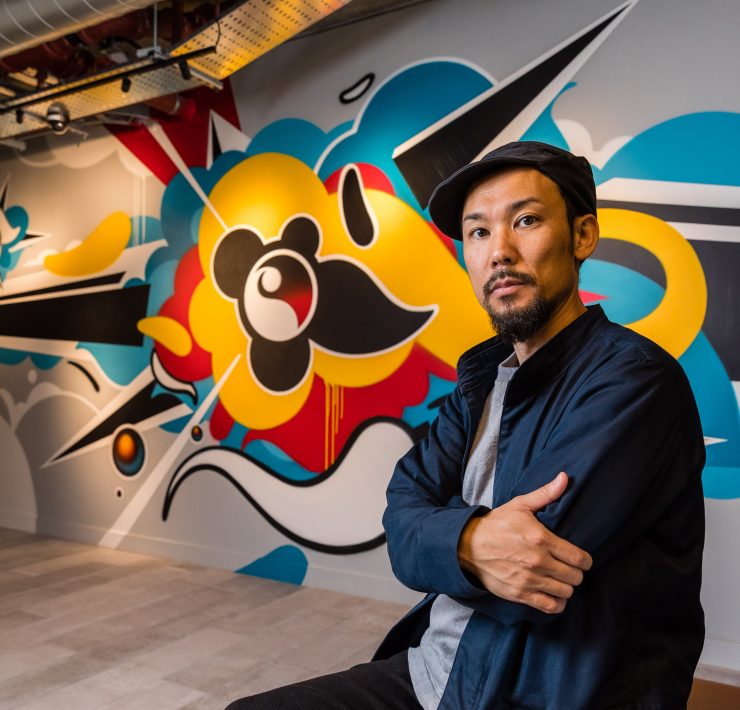 Artist Suiko in front of a piece of his grafitti