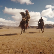 A mongolian on horseback hunting with an eagle