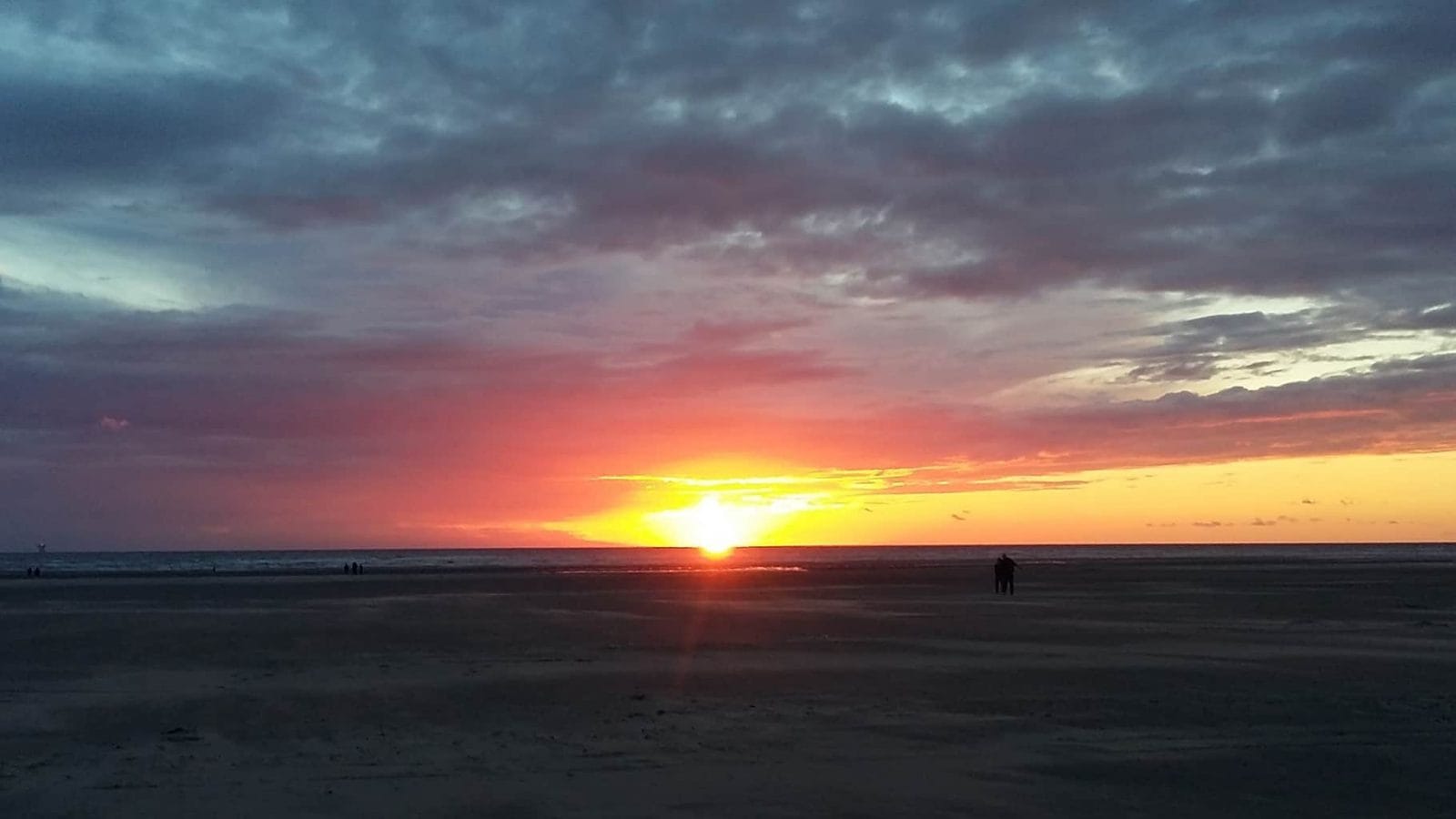 Picture of a sunset on Ainsdale beach. The sky is glowing below deep blue clouds