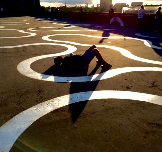 An image of a man lying on the floor as the sun creates a silhouette of his figure