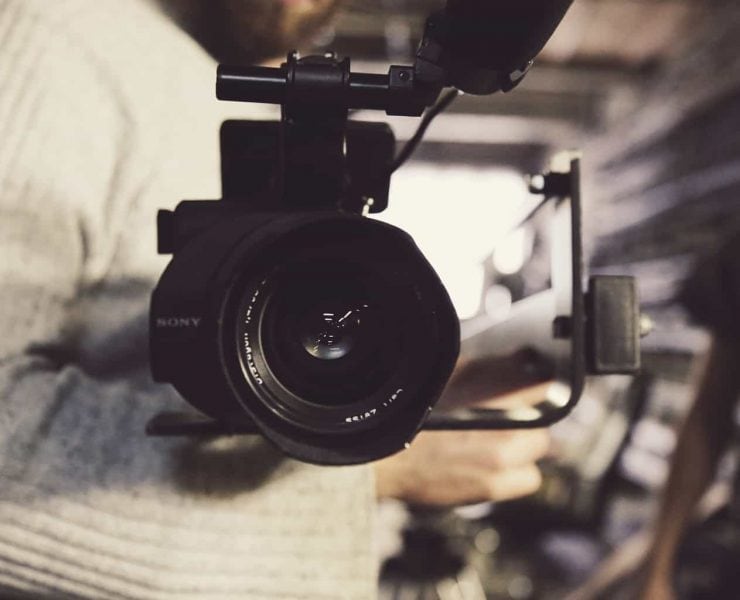 A close up image of a film camera being held by a cameraman