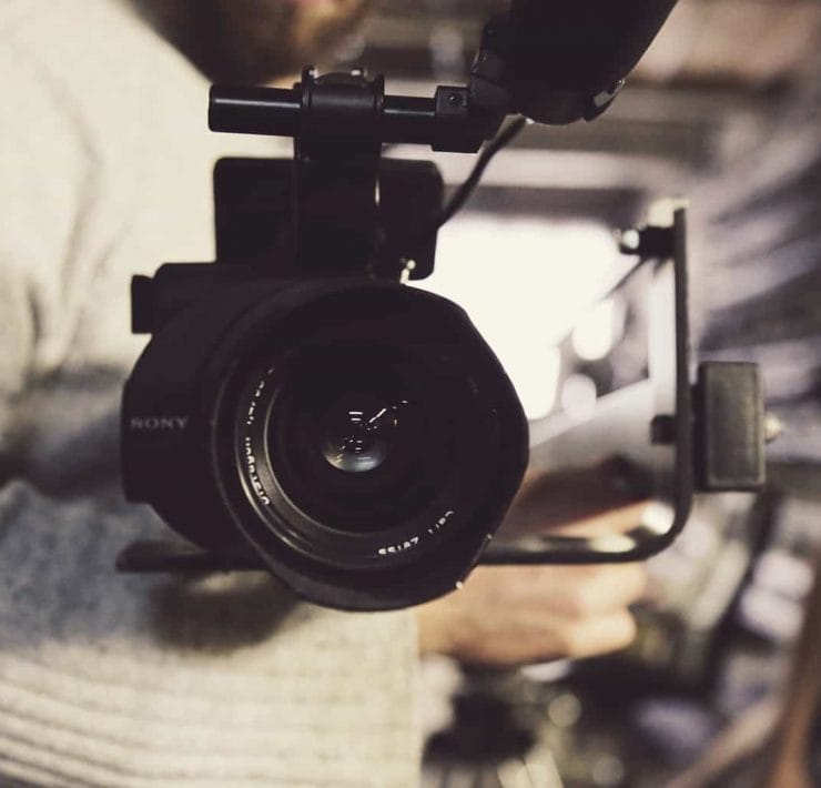 A close up image of a film camera being held by a cameraman