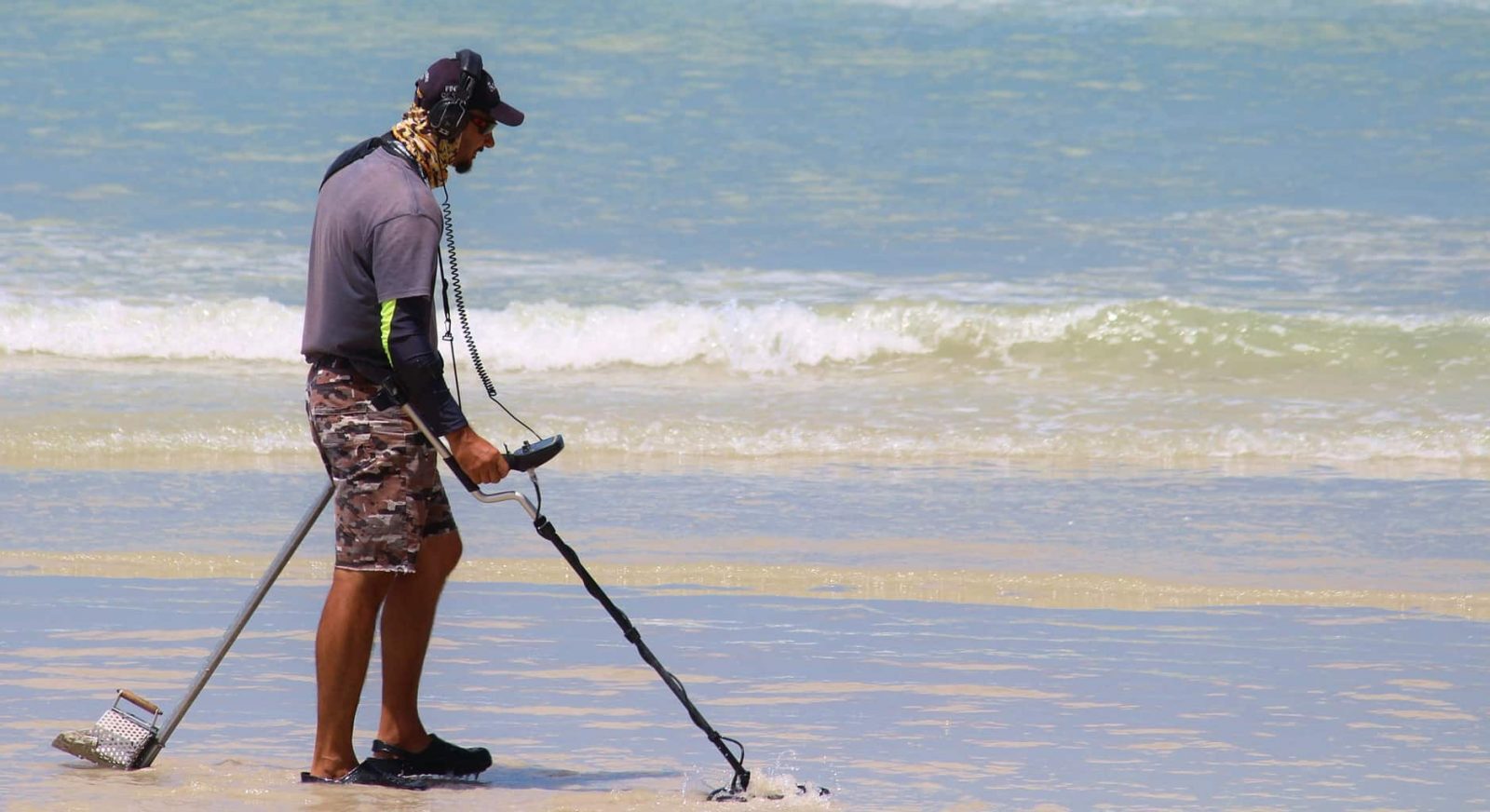 A man scouring the beach with a metal detector