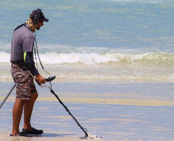 A man scouring the beach with a metal detector