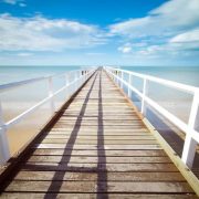 An image of a wooden jetty on a pristine clear blue sea