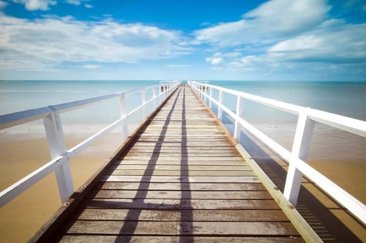An image of a wooden jetty on a pristine clear blue sea