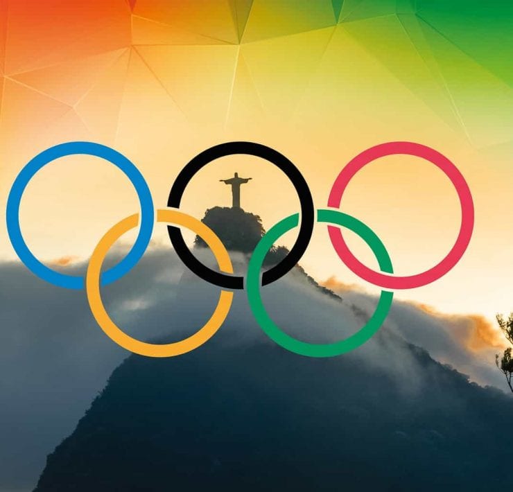 5 coloured Olympic rings with The Christ statue in Rio visible through them