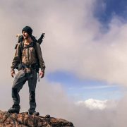 record breaking Adventurer Ash Dykes stands on top of a mountain in Madagascar. A chicken's head can be seen poking out of his rucksack. Pic taken by Suzanna Tierie