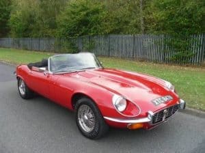 A red E Type Jaguar parked in a lay by