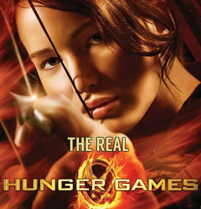 Jennifer Laurence on the poster for the first Hunger Games Film. He holds a bow and arrow in one hand. The words The Real have been added to the poster above the words Hunger Games