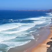 A beautiful beach viewed from a cliff top with sets of waves rolling in