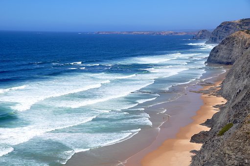A beautiful beach viewed from a cliff top with sets of waves rolling in