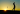 The silhouette of a golfer teeing off as the sun sets in the background