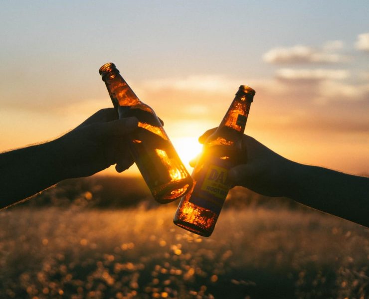 Hands 'Cheers' beer bottles together
