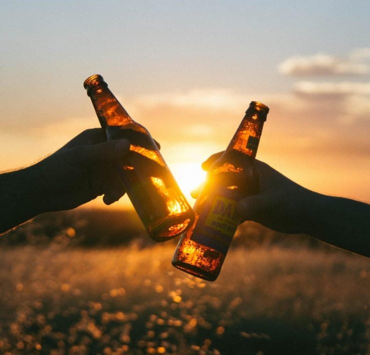 Hands 'Cheers' beer bottles together