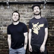 Sleaford Mods stood against a wall