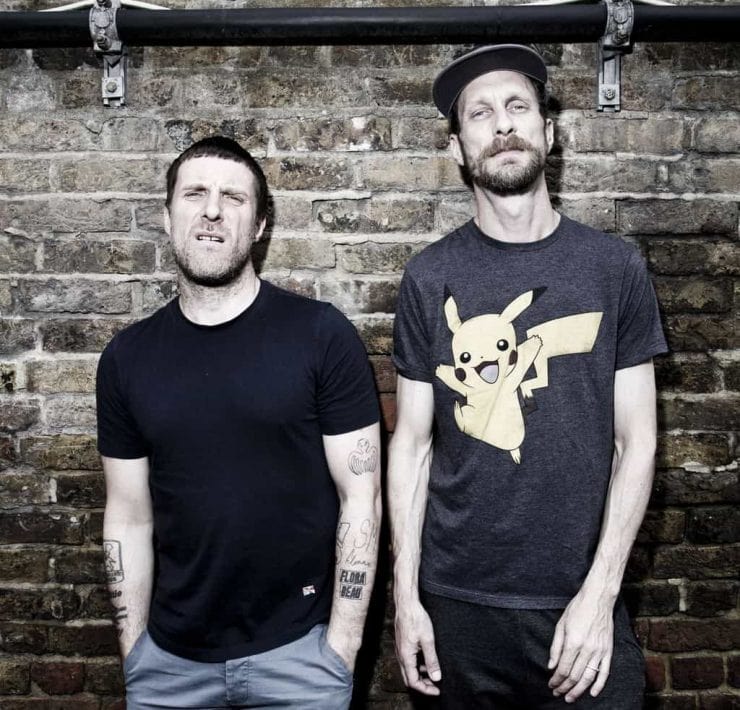 Sleaford Mods stood against a wall