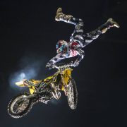 Travis Pastrana upside down holding onto a motorbike