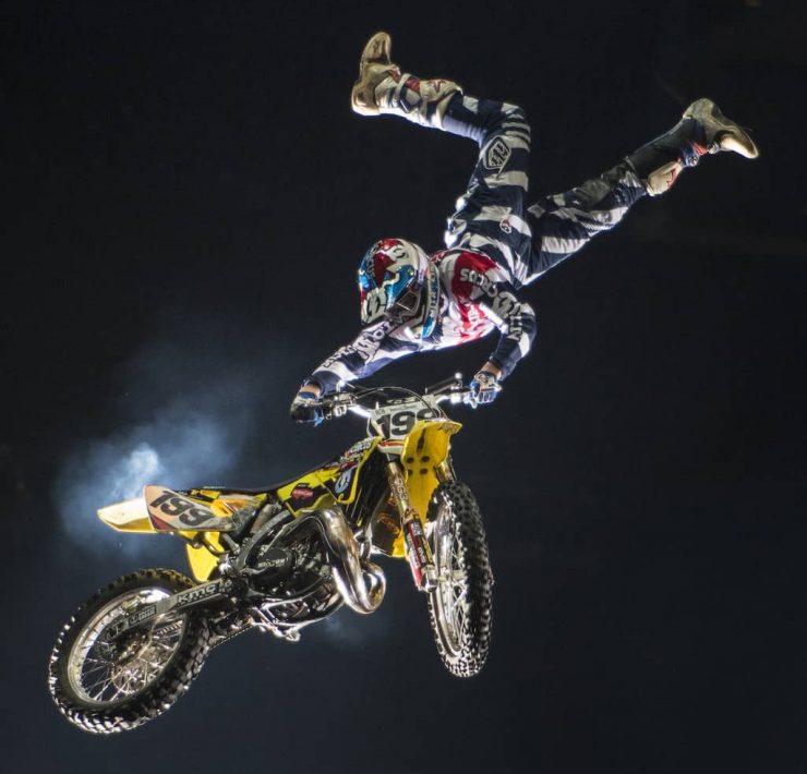 Travis Pastrana upside down holding onto a motorbike