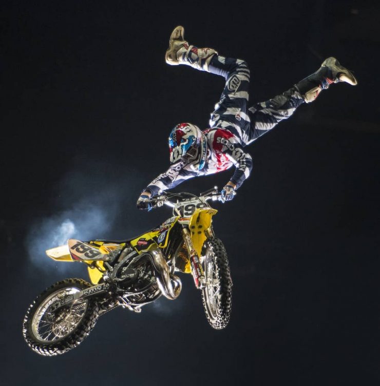 Travis Pastrana upside down holding onto a motorbike