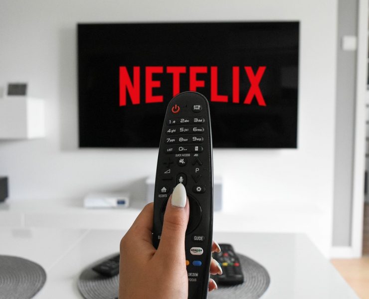 woman pointing remote at netflix