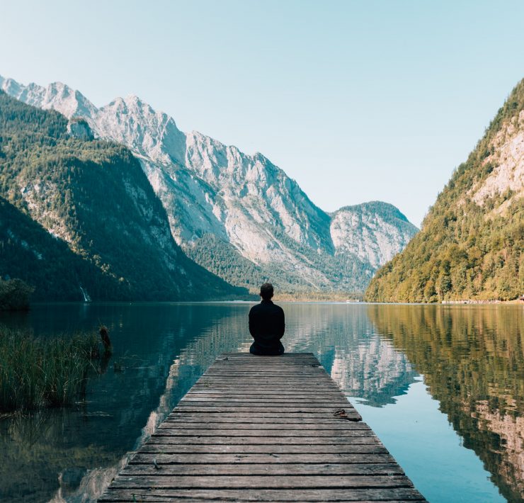 A masn sitting by a lake in the mountains