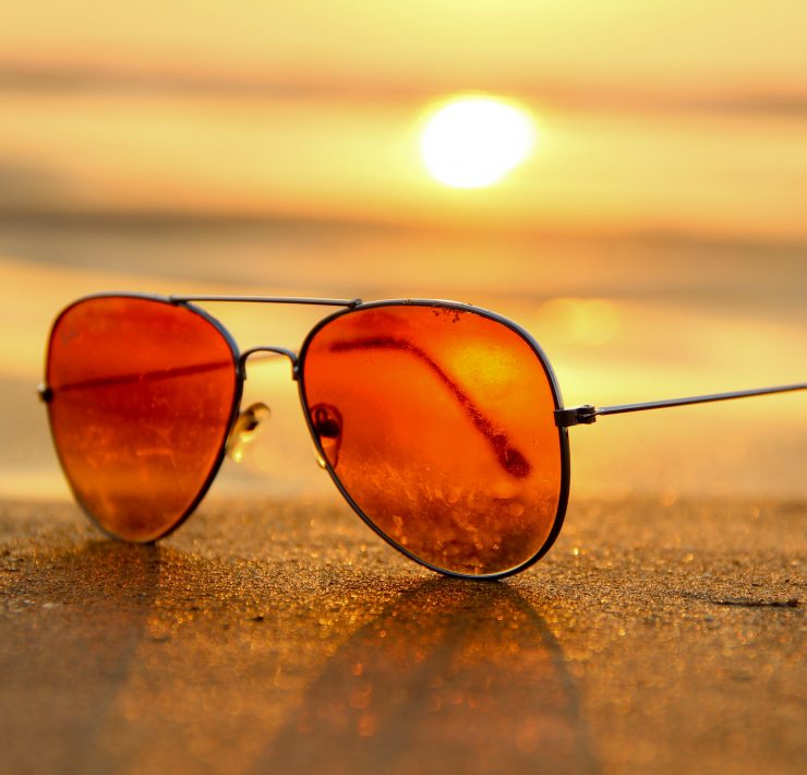 Sunglasses on a beach in front of a sunset