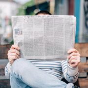 A man seated on a bench reading a newspaper
