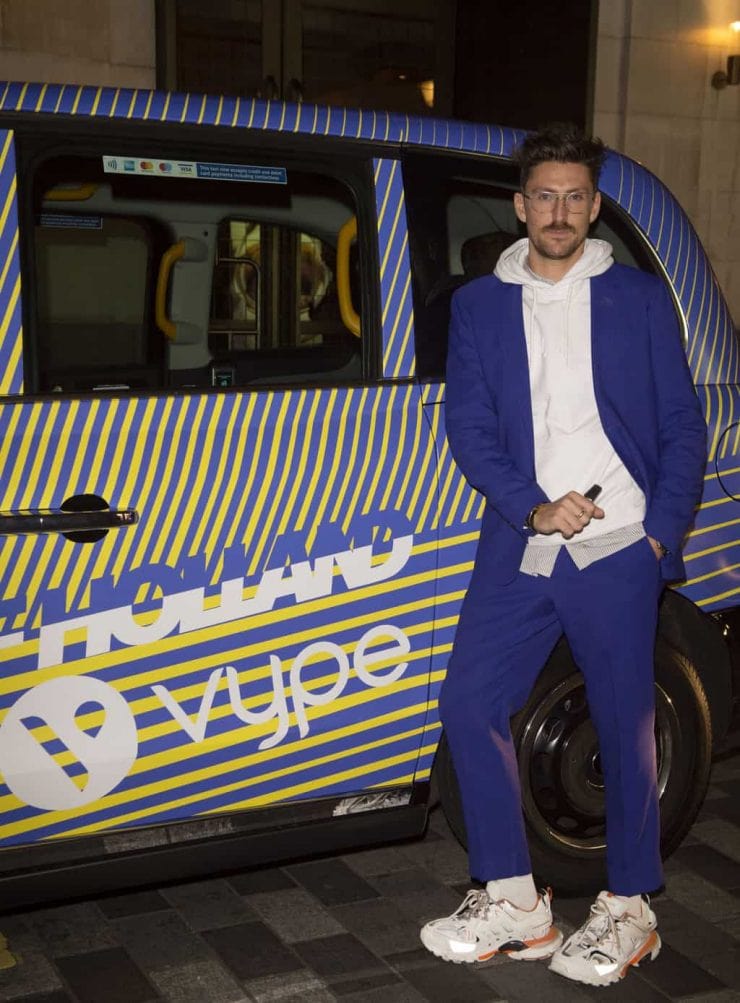 Fashion designer Henry Holland poses next to a London taxi