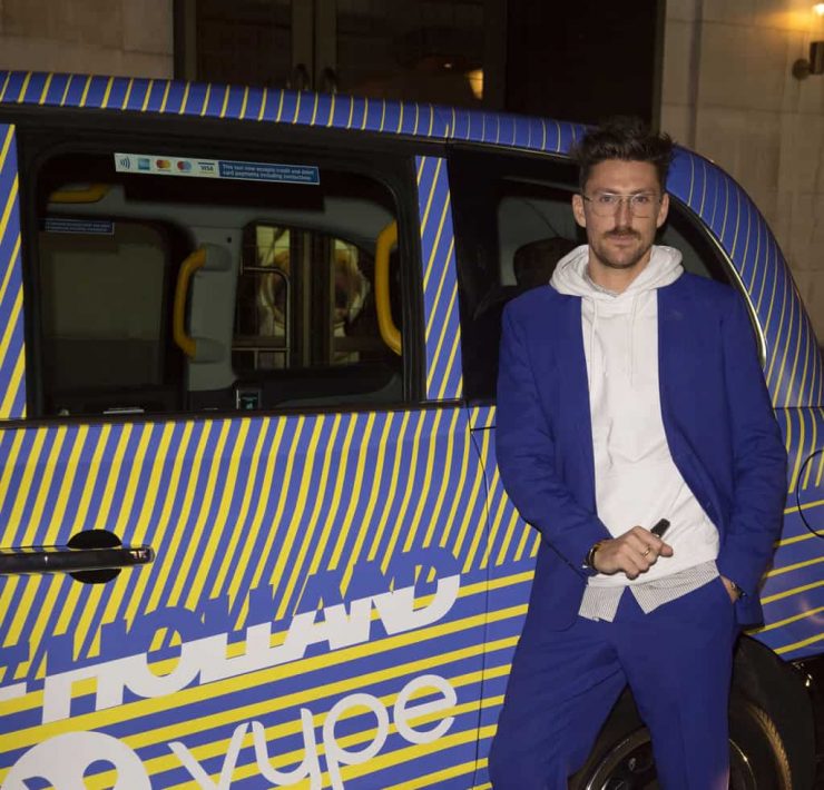 Fashion designer Henry Holland poses next to a London taxi