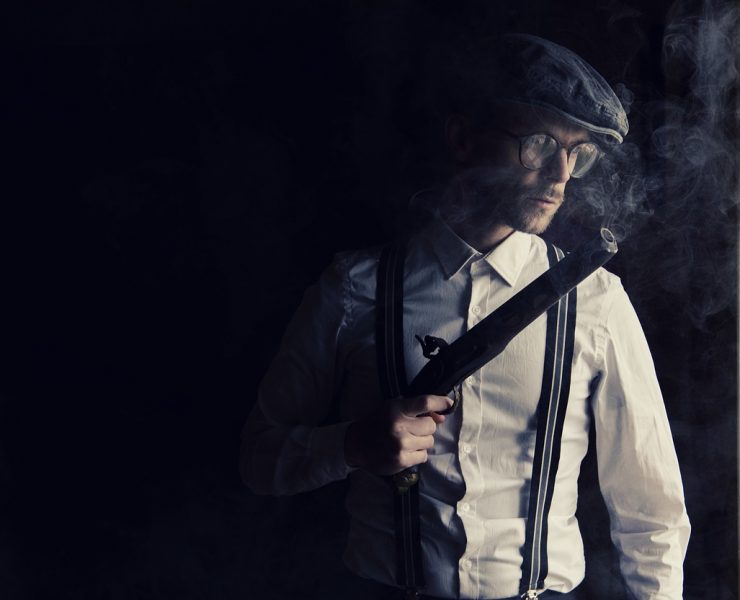 gangster holding a gun in the shadows