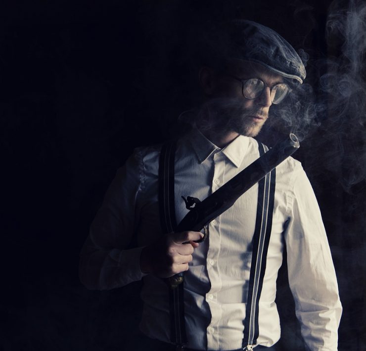 gangster holding a gun in the shadows