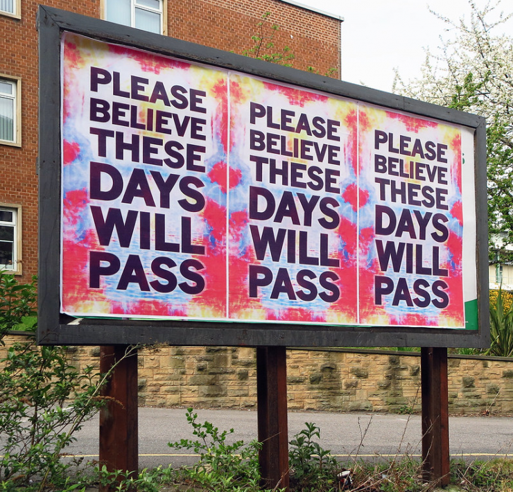 A sign reads 'Please believe these days will pass'