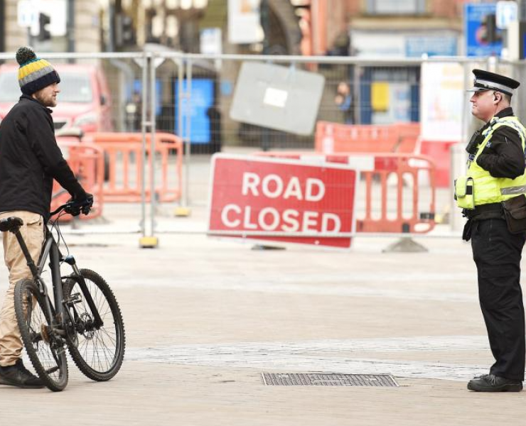 Policeman speaking to a man with a bike during lockdown