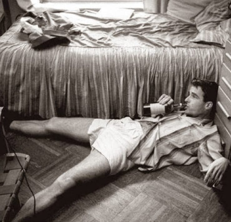 Man drunk on the floor clutching a bottle