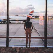 Girl in airport looking through a window at a British airways plane