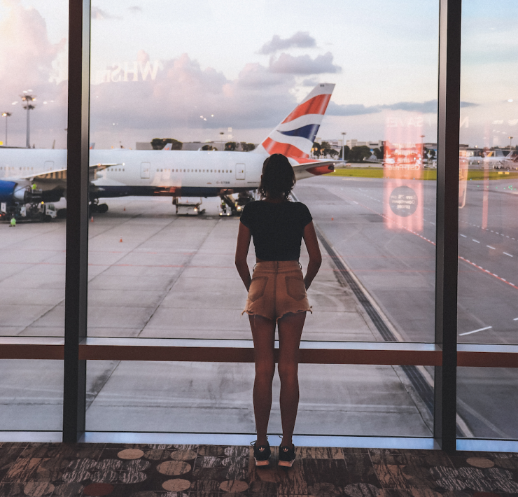 Girl in airport looking through a window at a British airways plane