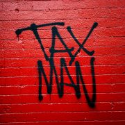 'Tax Man' written in graffiti on a red brick wall