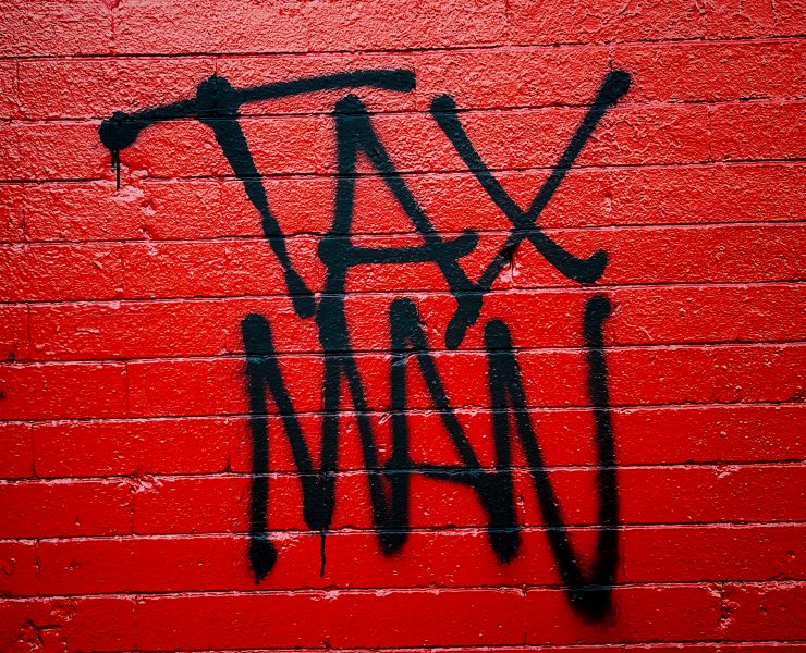 'Tax Man' written in graffiti on a red brick wall