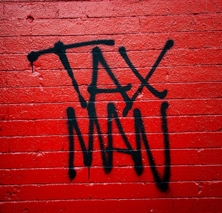 'Tax Man' written in graffiti on a red brick wall