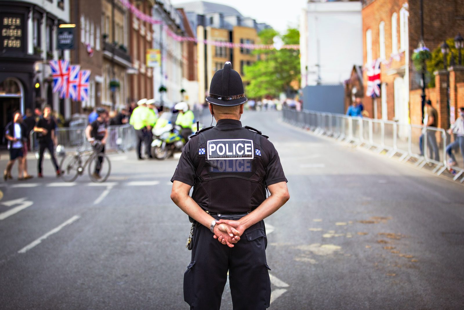 Male policeman standing in the middle of a road with his back to camera
