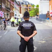 Male policeman standing in the middle of a road with his back to camera