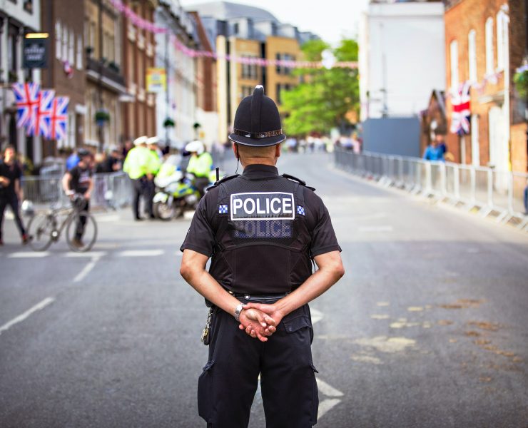 Male policeman standing in the middle of a road with his back to camera