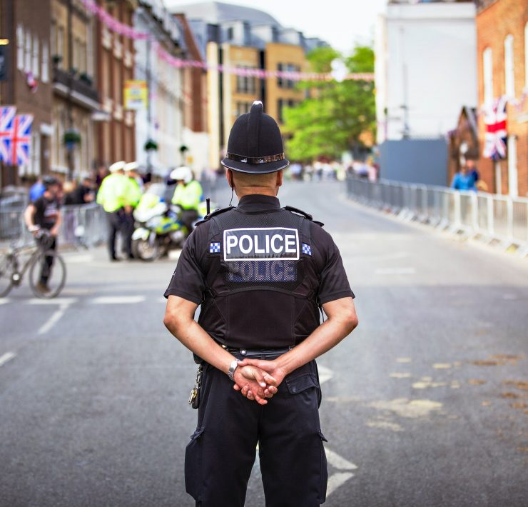 Male policeman standing in the middle of a road with his back to camera