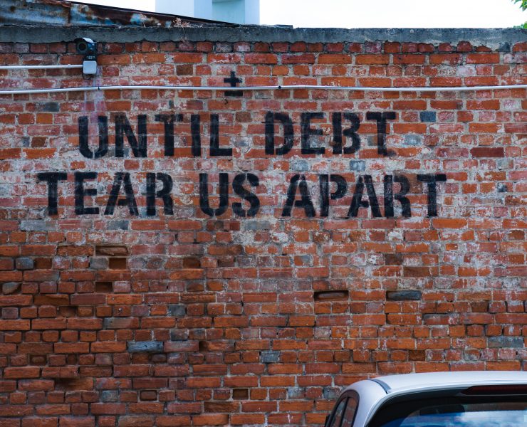 until debt tear us apart graffiti on a brick wall