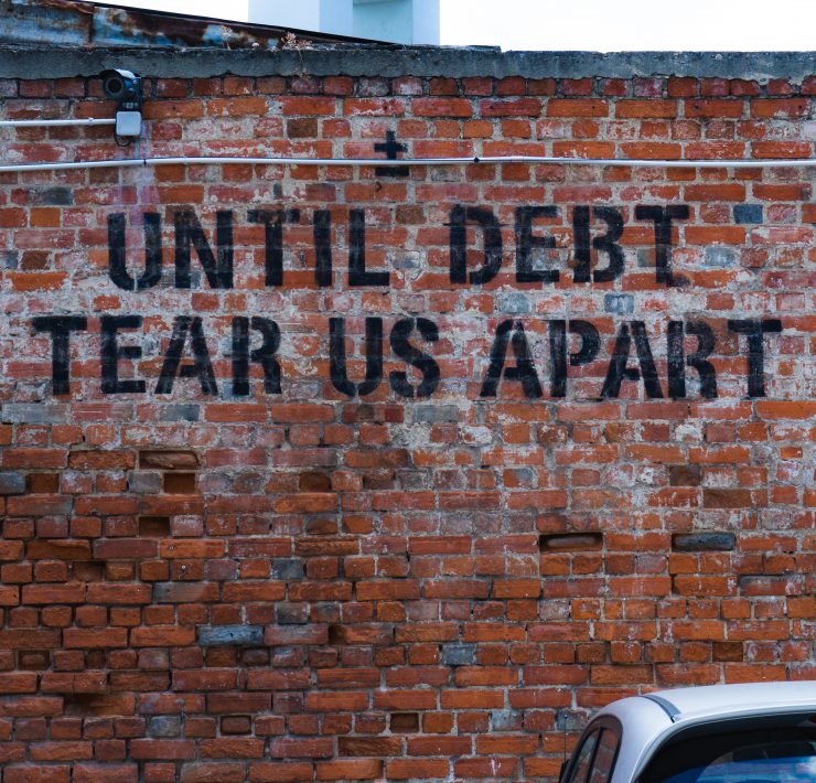 until debt tear us apart graffiti on a brick wall