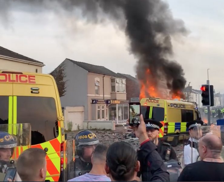 a crowd watch a riot van on fair in Southport